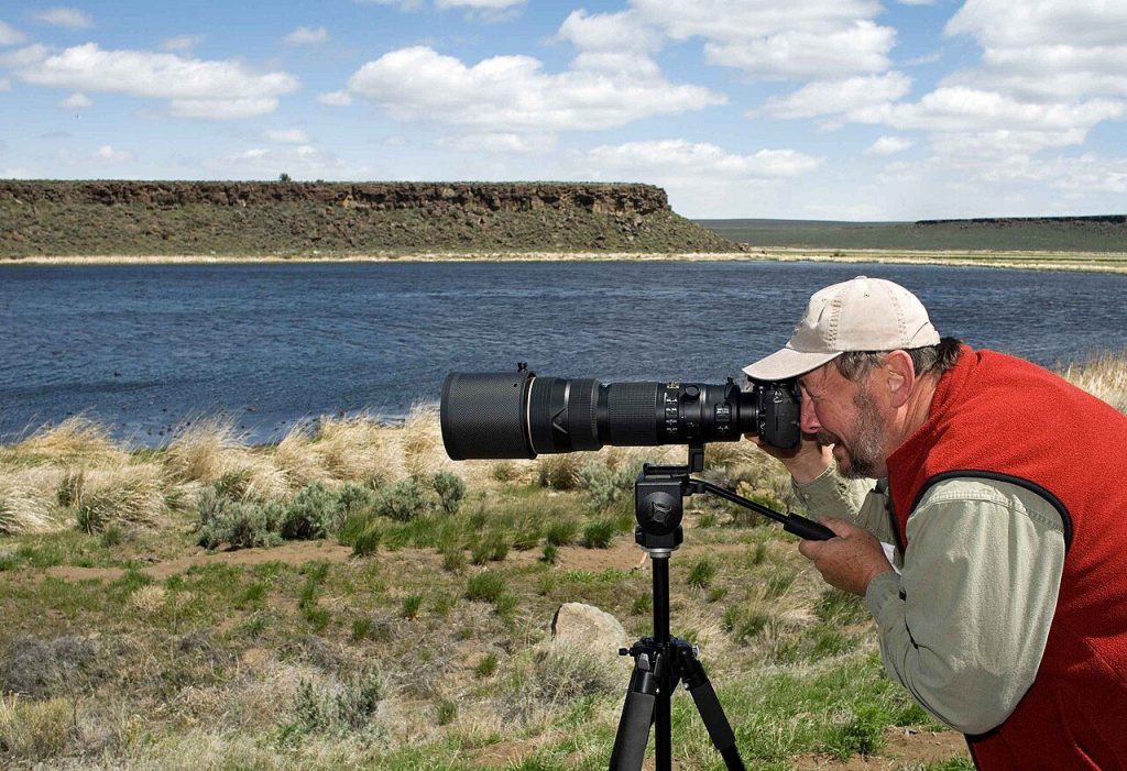 Photographer with a telephoto camera in the field