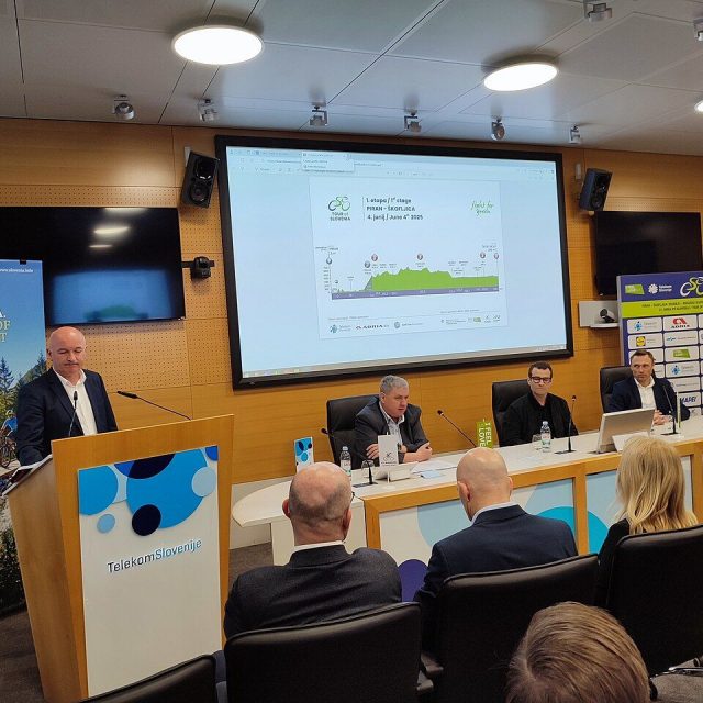 Speaker at a press conference with presentation screen