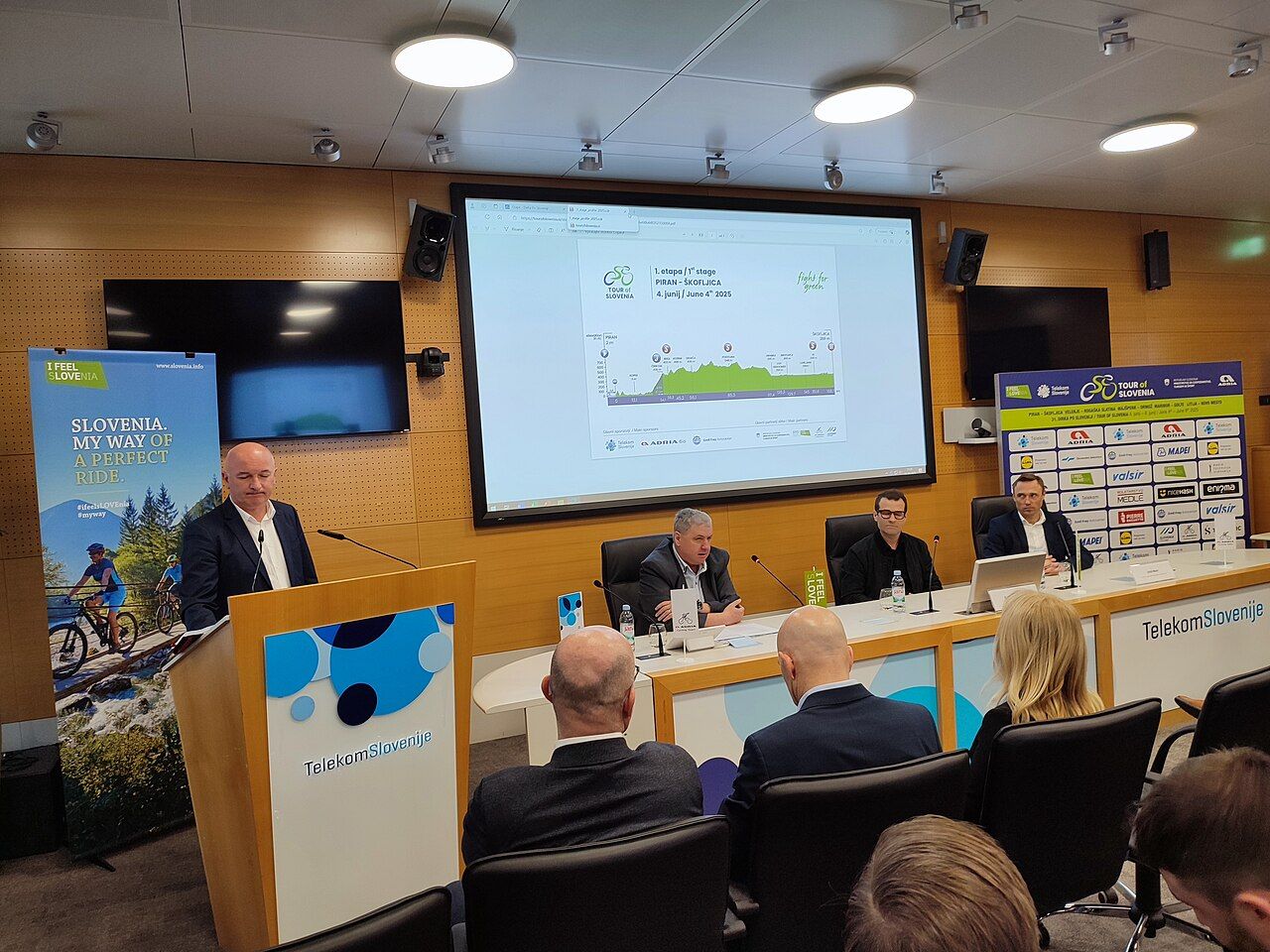 Speaker at a press conference with presentation screen